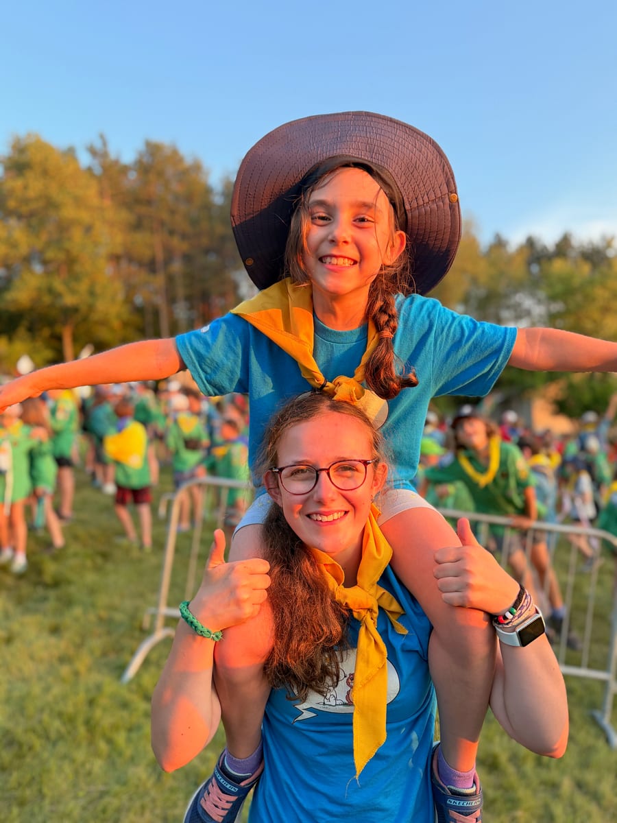 Une animatrice porte une jeune castor sur ses épaules lors d’un rassemblement ; toutes les deux sourient.